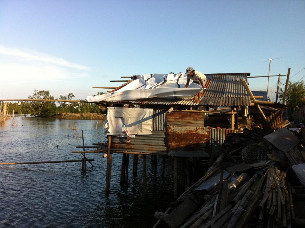 フィリピン　IOMの配布したビニールシートを使用して崩れた屋根をカバーします　© IOM 2014